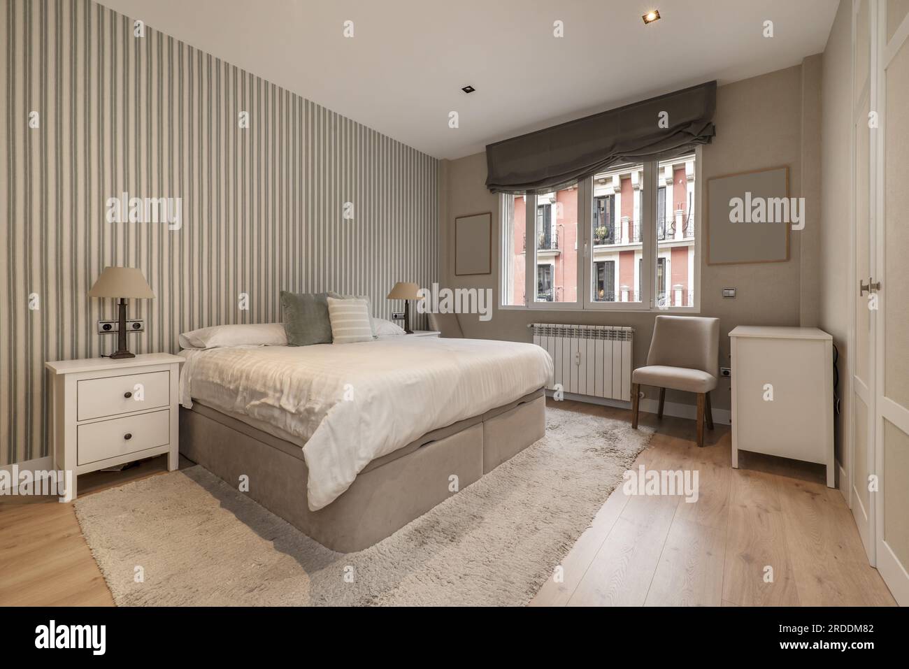 Camera da letto con un letto matrimoniale con comodini in legno bianco,  pavimenti in legno e una pedana pieghevole sotto il letto Foto stock - Alamy