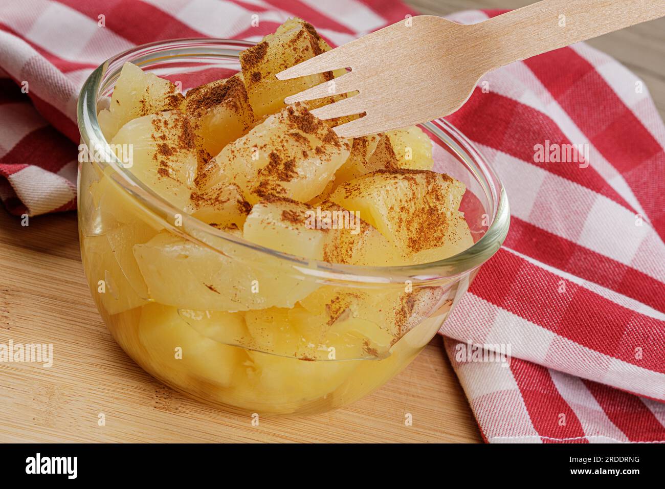 Un primo piano di deliziosi pezzi di ananas e Cinnamon Power in Juicy Syrup su uno sfondo di legno con spazio per la copia Foto Stock