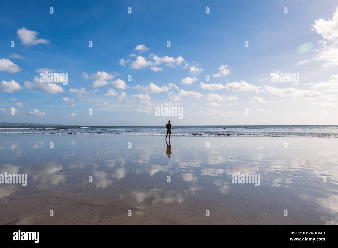 Un uomo in piedi sulla spiaggia di kuta, nel sud di Bali, Indonesia. Foto Stock