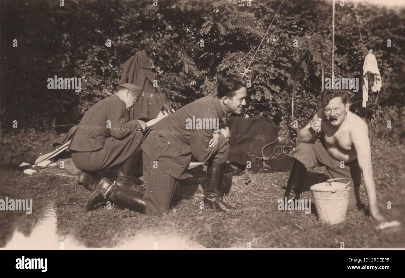 rara foto di vita militare della seconda guerra mondiale (seconda guerra mondiale) un soldato sta pulendo i denti sopra un cesto in un campo militare. mentre si sta lavando i denti un altro soldato lo sta osservando in modo closly mentre sta duellando correttamente. Foto Stock