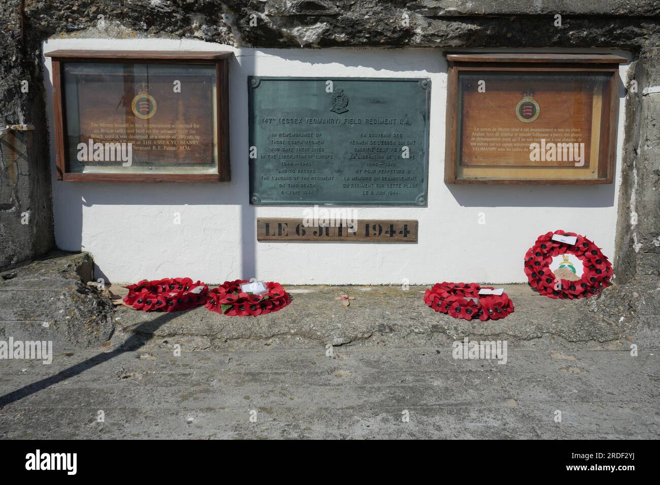 Targhe commemorative e ghirlande di papavero su un emplacemdnt tedesco da 88 mm sulla spiaggia di Asnelles. Asnelles Francia. Foto Stock
