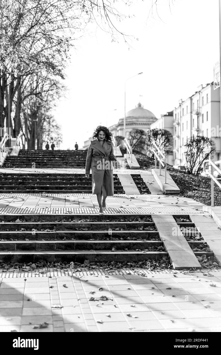 Giovane donna che cammina lungo i gradini della strada attraverso la città autunnale Foto Stock