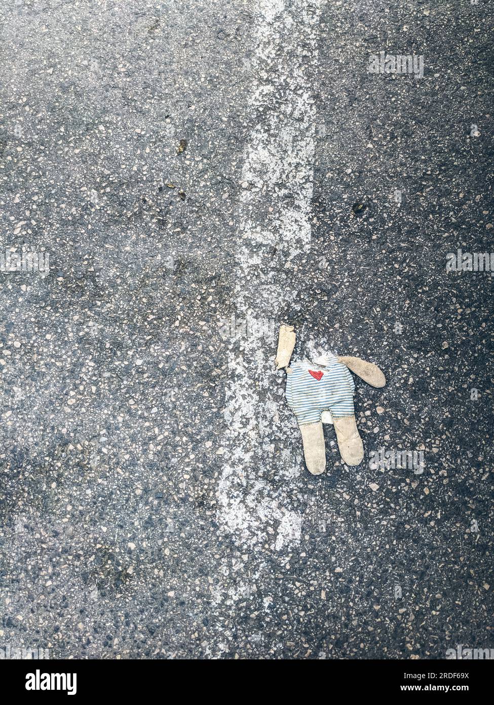 Un giocattolo sporco senza testa giace sull'asfalto Foto Stock