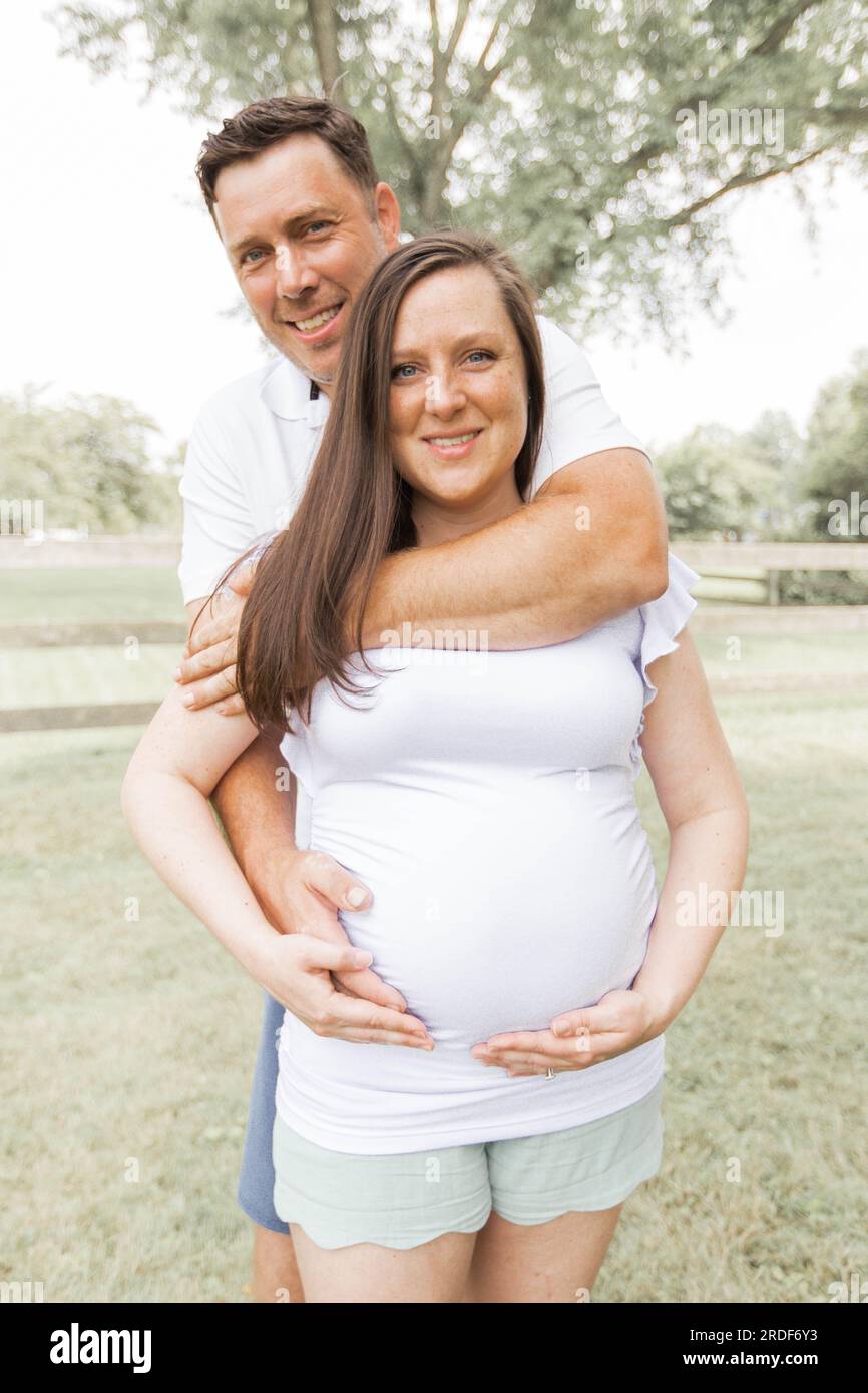 Coppia sorridente in bianco con le mani su Pregnant Belly Foto Stock