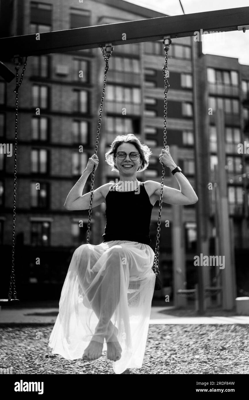 Una donna oscilla su un altalena, atmosfera estiva. Foto Stock