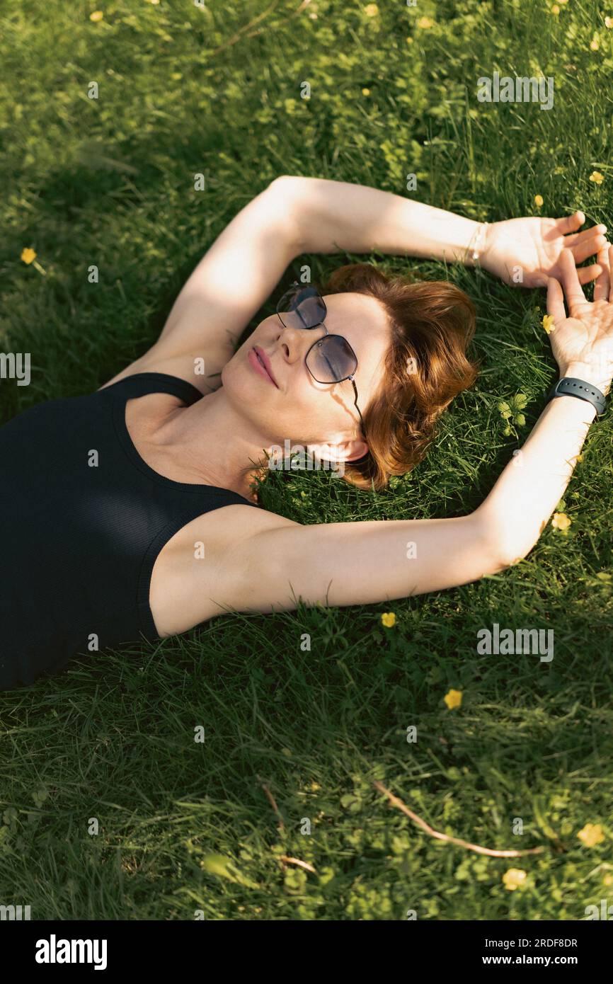 Una donna giace sull'erba, nell'atmosfera estiva. Foto Stock
