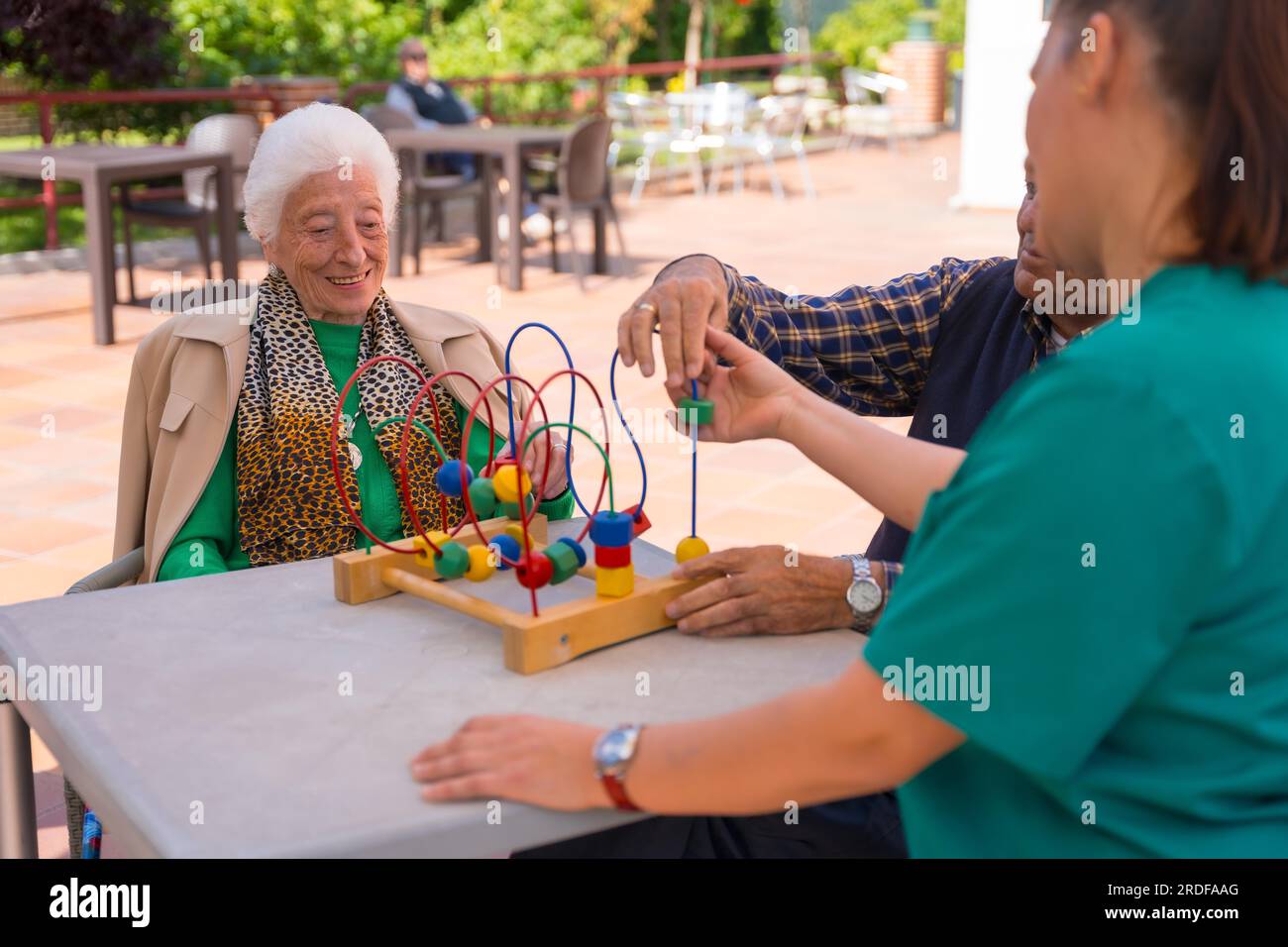 Due anziani nel giardino di una casa di cura o di una casa di riposo che giocano con giochi per migliorare la mobilità Foto Stock