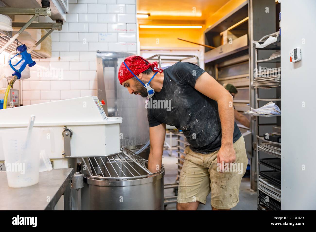 fornaio maschio di panificio nella bottega di panificio artigianale che prepara gli impasti naturali nelle macchine Foto Stock