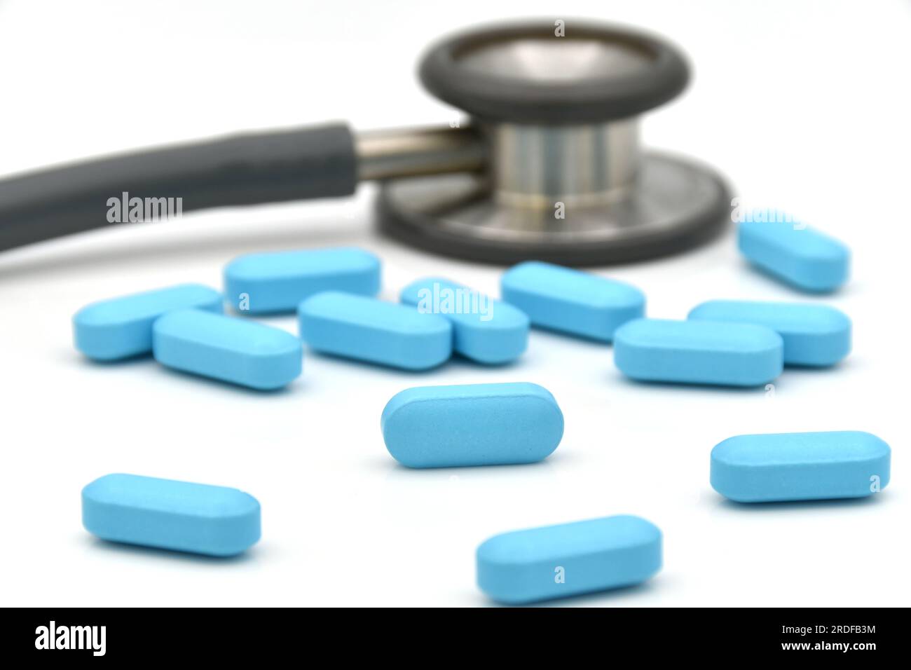 Stetoscopio e Blue caplet medicine su sfondo bianco nel concetto di diagnosi e prescrizione medica. Foto Stock