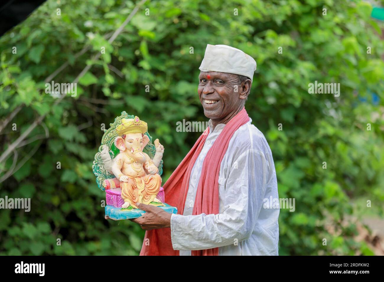 Vecchio indiano che tiene in mano l'idolo di Lord Ganesha, vecchio e povero Foto Stock