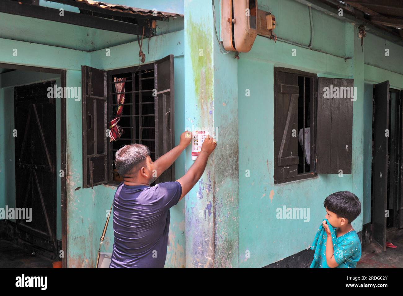 Sylhet City Corporation personale del Dipartimento della salute incollare adesivi sul muro della casa. Da giugno Sylhet City Corporation e Save the Children stanno conducendo programmi di sensibilizzazione pubblica per prevenire la diffusione della dengue in diversi quartieri della città di Sylhet. Sylhet, Bangladesh. Foto Stock