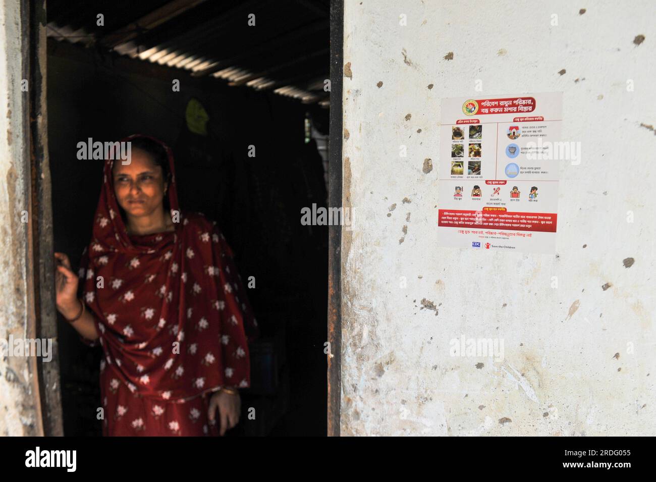 Sylhet City Corporation personale del Dipartimento della salute incollare adesivi sul muro della casa. Da giugno Sylhet City Corporation e Save the Children stanno conducendo programmi di sensibilizzazione pubblica per prevenire la diffusione della dengue in diversi quartieri della città di Sylhet. Sylhet, Bangladesh. Foto Stock