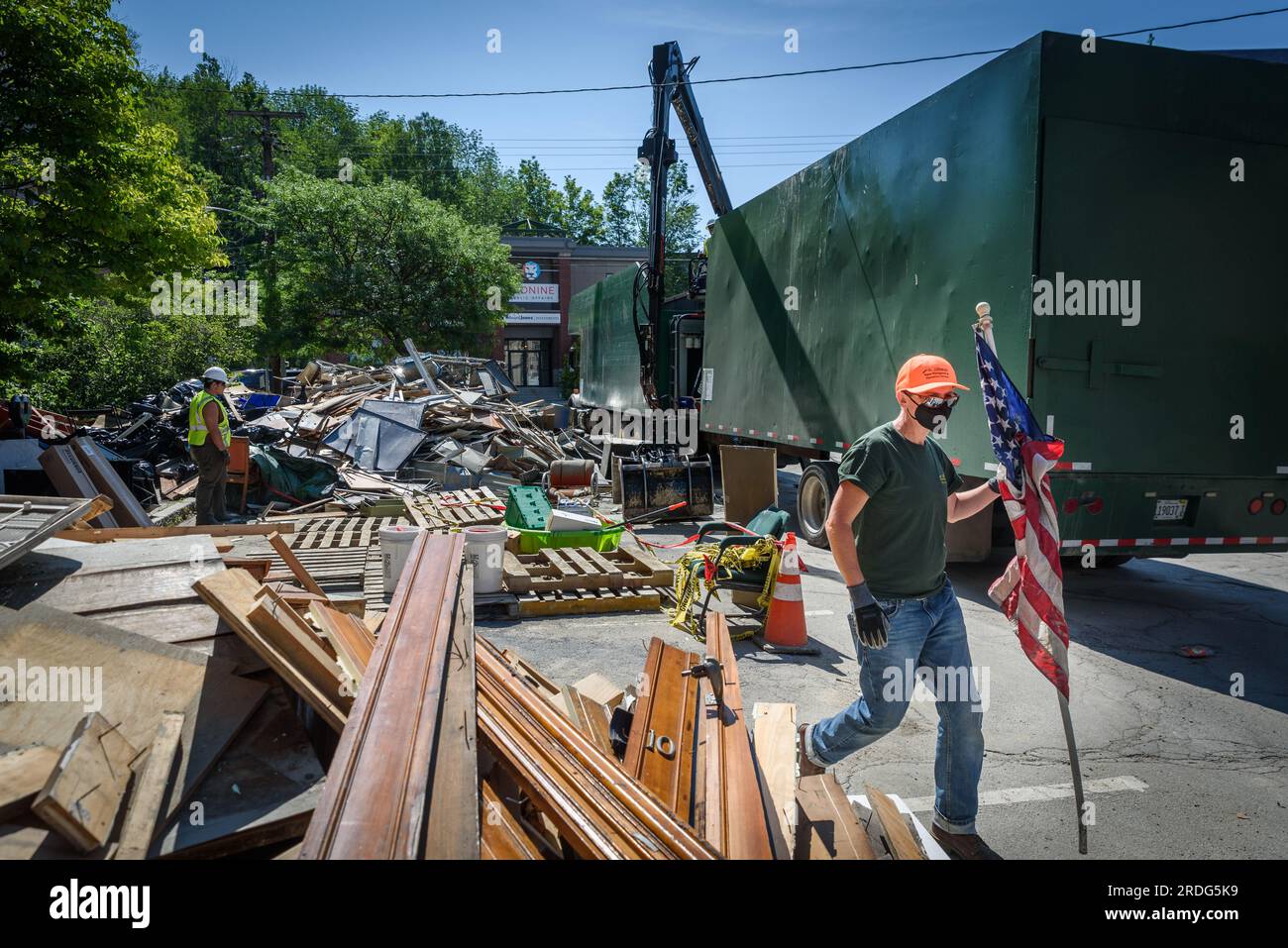 Mia Roethlein del Vermont Solid Waste and Recycling Program salva una bandiera americana dalle pile di detriti inondati di Montpelier, USA. Foto Stock