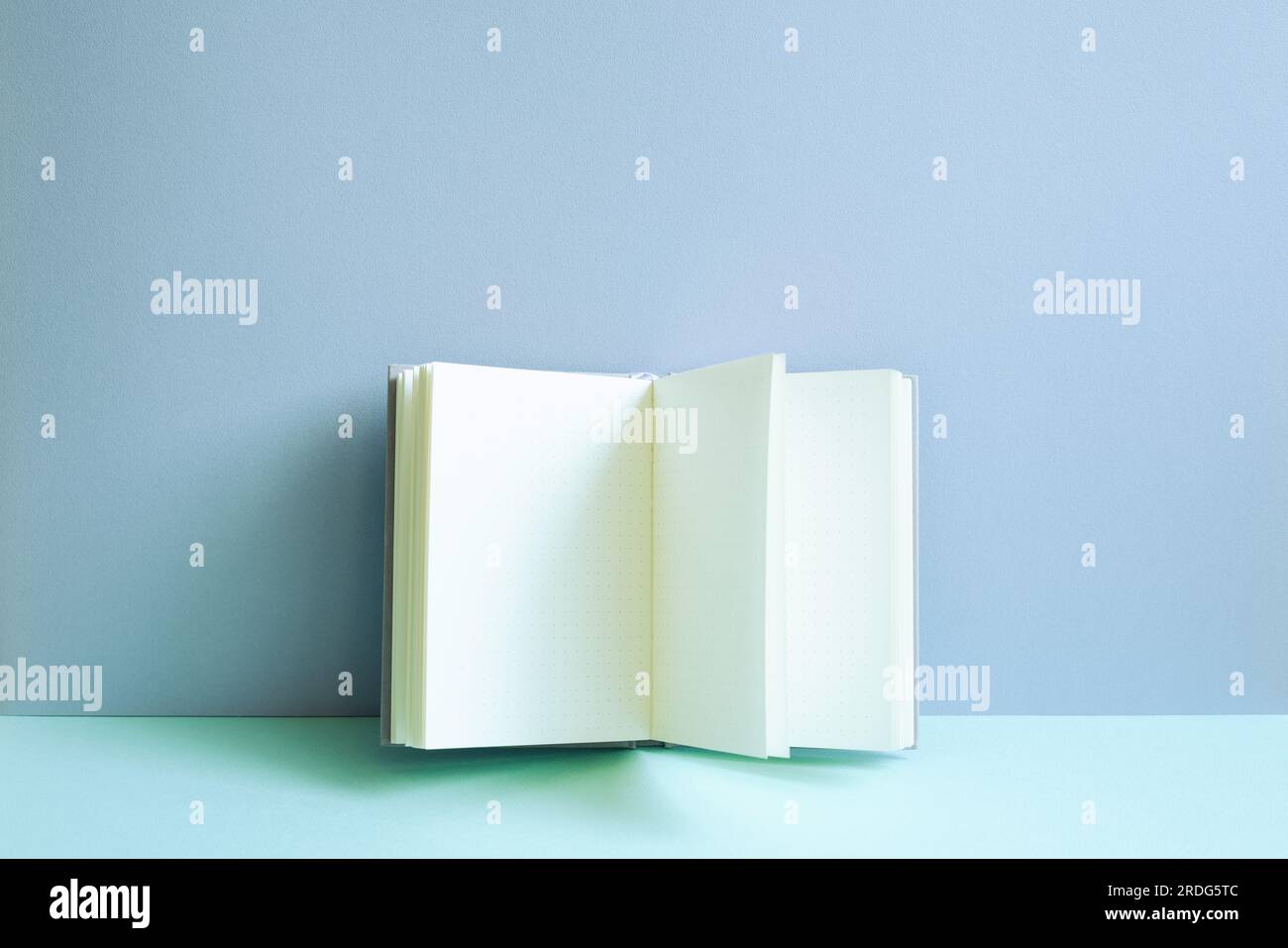 Aprire il notebook sulla scrivania blu. sfondo a parete blu Foto Stock