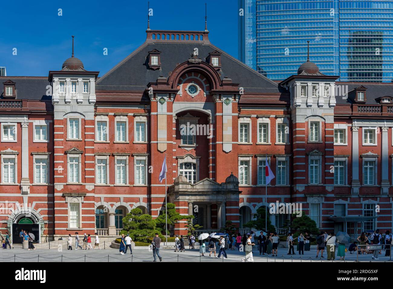 TOKYO, GIAPPONE - 16 LUGLIO 2023: Piccole folle di persone intorno all'edificio in mattoni rossi della stazione centrale di Tokyo in un caldo giorno estivo Foto Stock