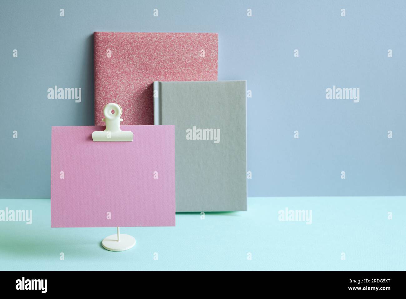 Notebook e memo pad rosa su scrivania blu. sfondo a parete blu. area di lavoro Foto Stock