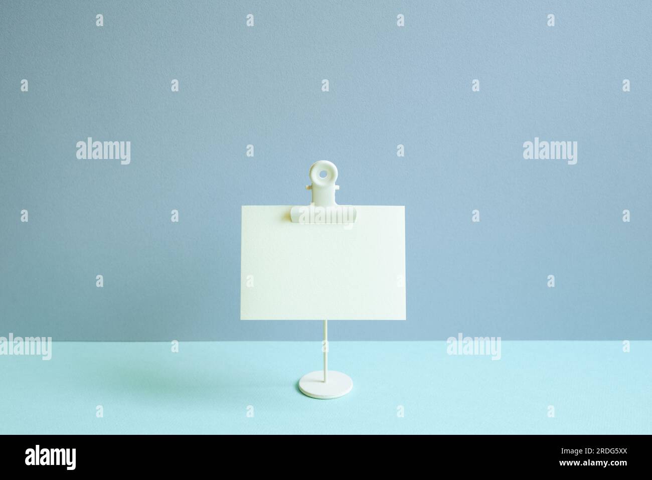 Cialda per appunti vuota e supporto sulla scrivania blu. sfondo a parete blu Foto Stock