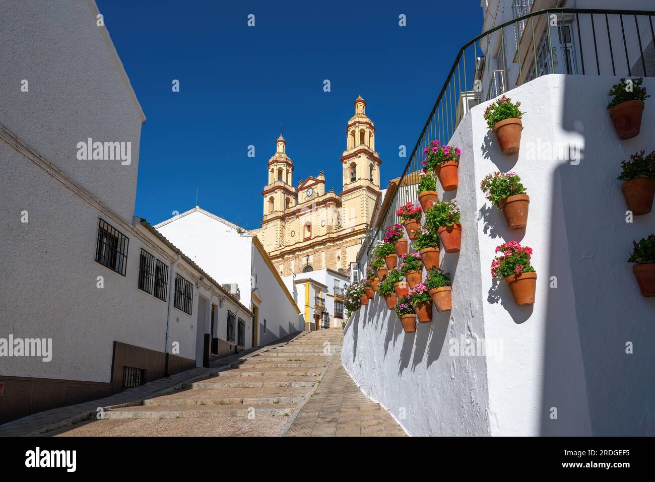 Chiesa di Nuestra Senora de la Encarnacion e scale con vasi di fiori - Olvera, Andalusia, Spagna Foto Stock