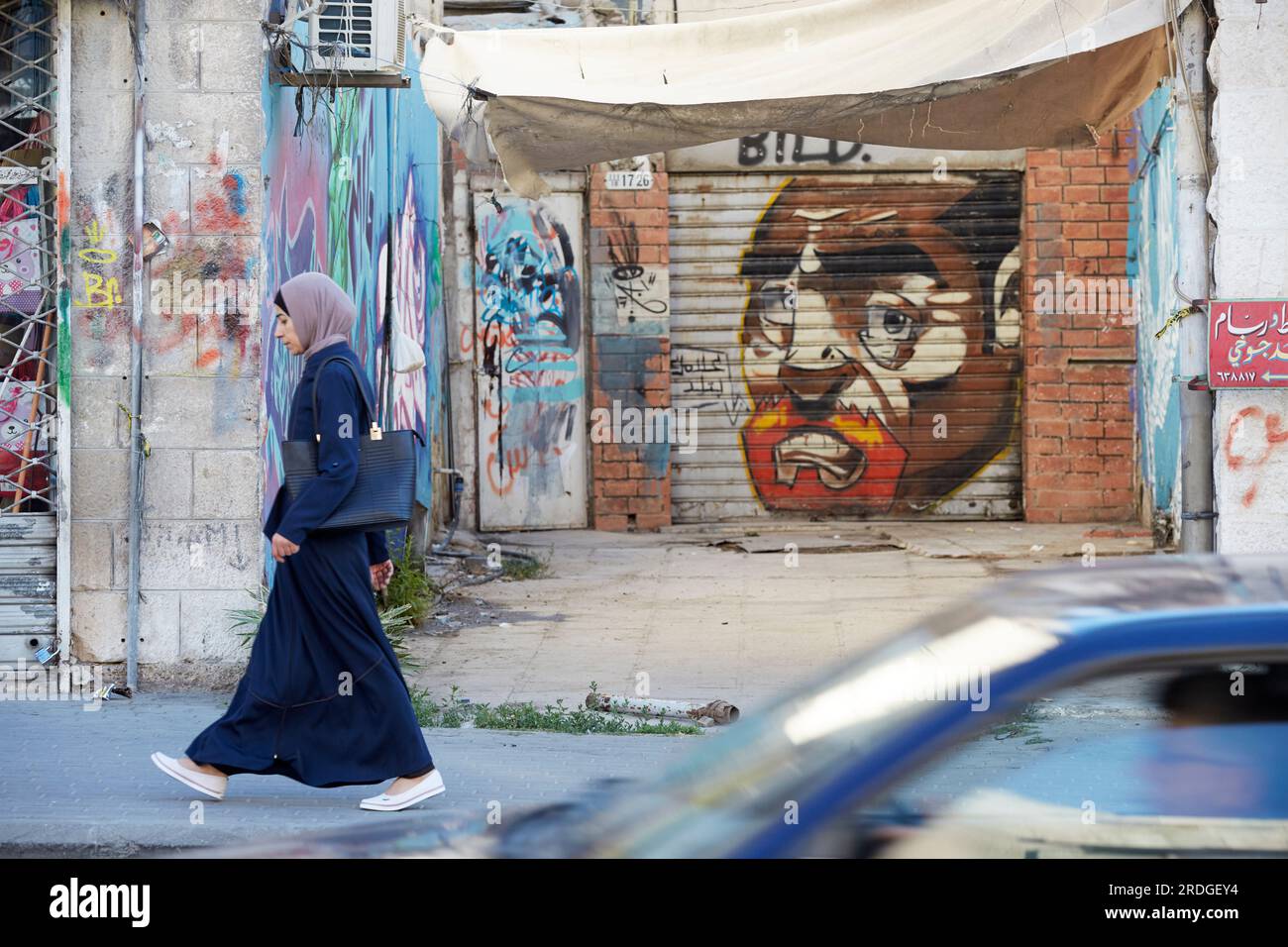 Donna che passa davanti agli grafitti di strada, Amman, Jordan Foto Stock