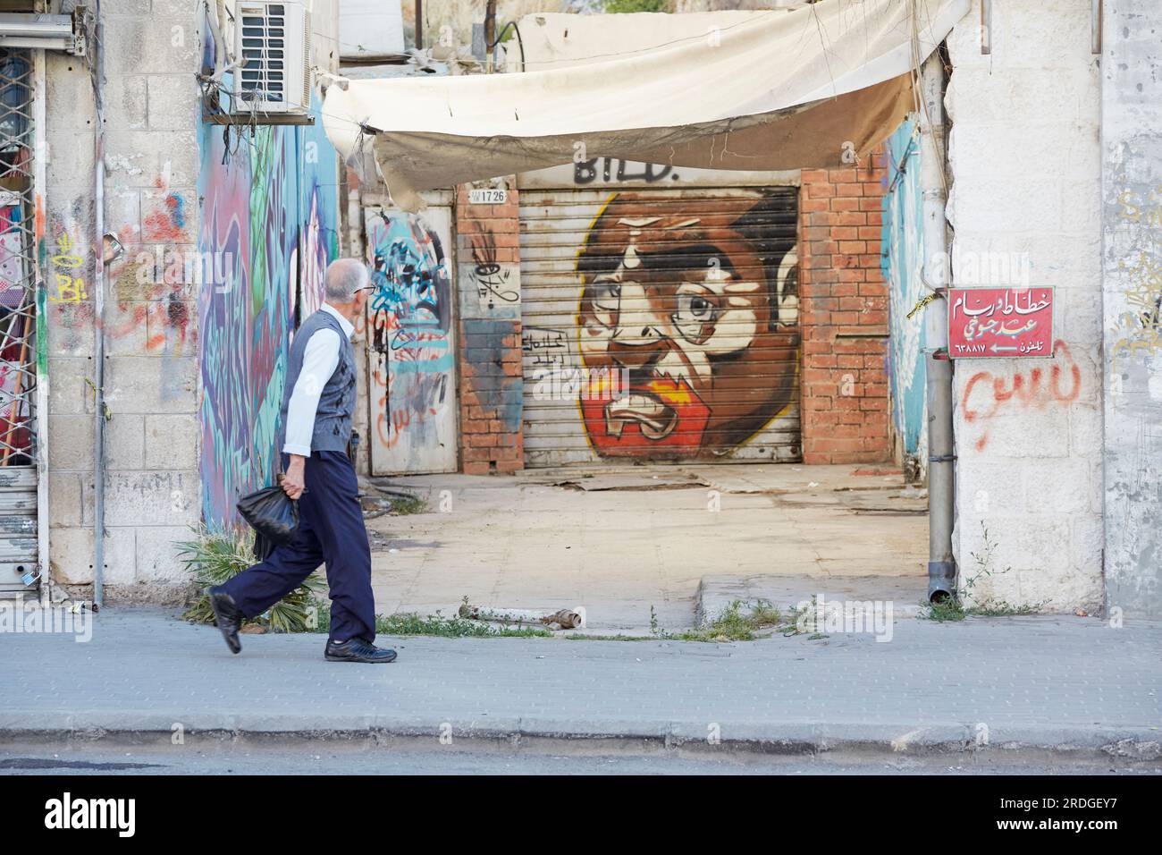 Uomo che passa davanti agli grafitti di strada, Amman, Jordan Foto Stock