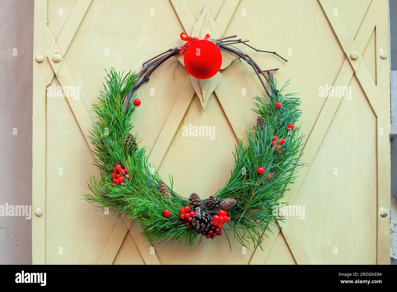 Corona di Natale, baubles appesi sullo sfondo delle persiane della casa. Tradizionale corona di natale rustico di rami di abete rosso, decorata con Foto Stock