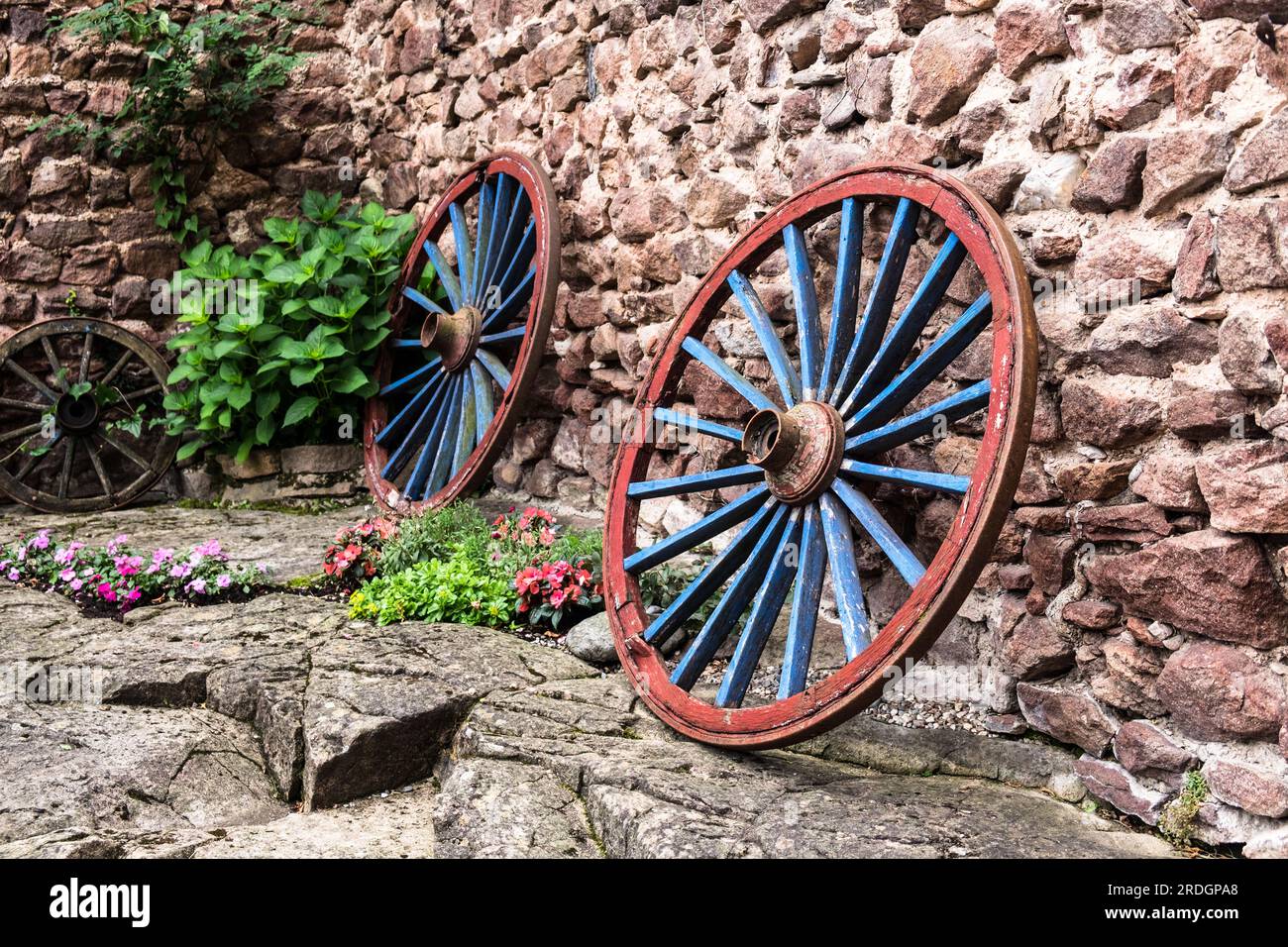 Dekorative Kutschenräder an einer Steinmauer Foto Stock