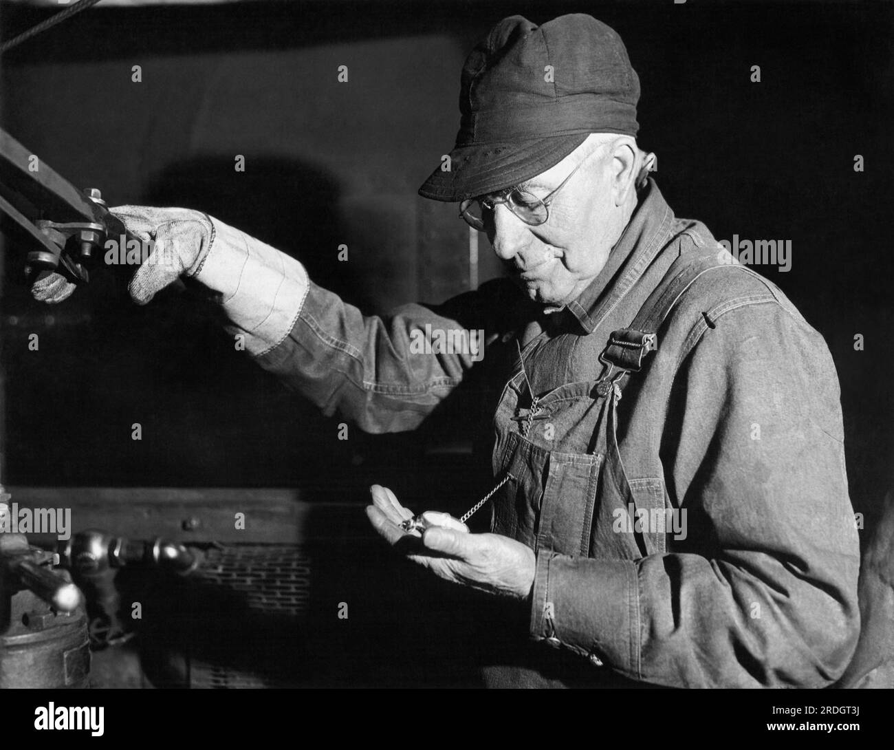 Chicago, Illinois: c. 1928 Un veterano ingegnere della Rock Island Railroad Line controlla il suo orologio durante la sua ultima corsa prima di ritirarsi dopo 52 anni. Foto Stock
