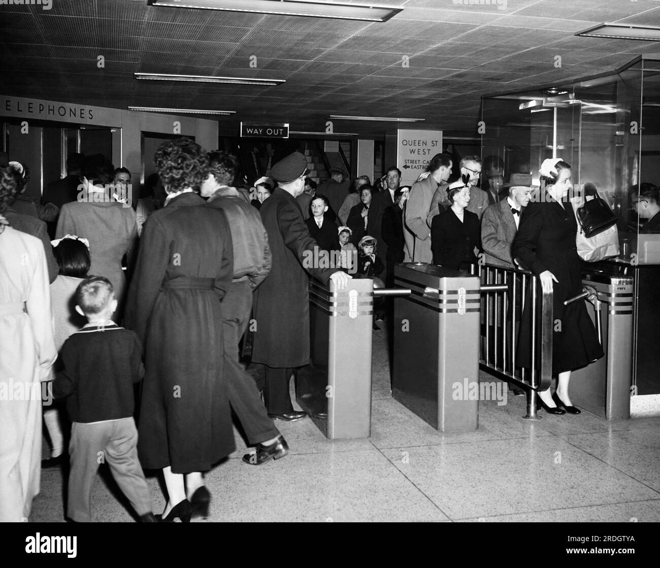 Toronto, Canada: c. 1957 Una scena nella stazione della metropolitana di Queen Street con i passeggeri che attraversano i tornelli. Foto Stock