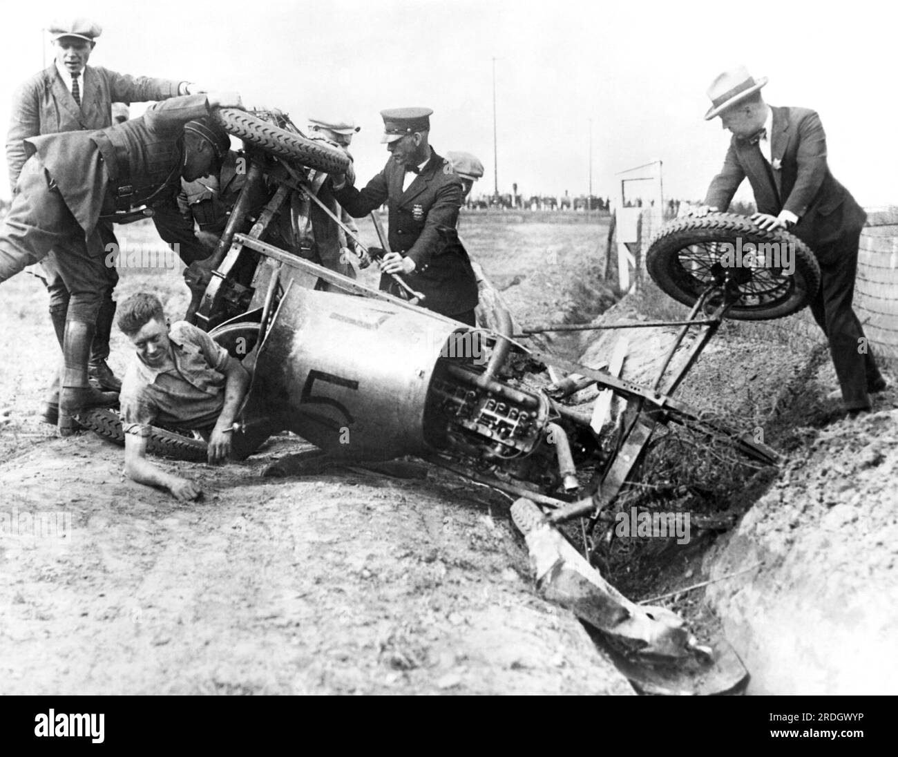 St Paul, Minnesota: 23 giugno 1926 Un pilota di auto da corsa viene aiutato dal suo veicolo dopo essersi schiantato. Le ruote anteriori si erano sparse durante la guida a 80 km/h, costringendolo nel fossato. Foto Stock