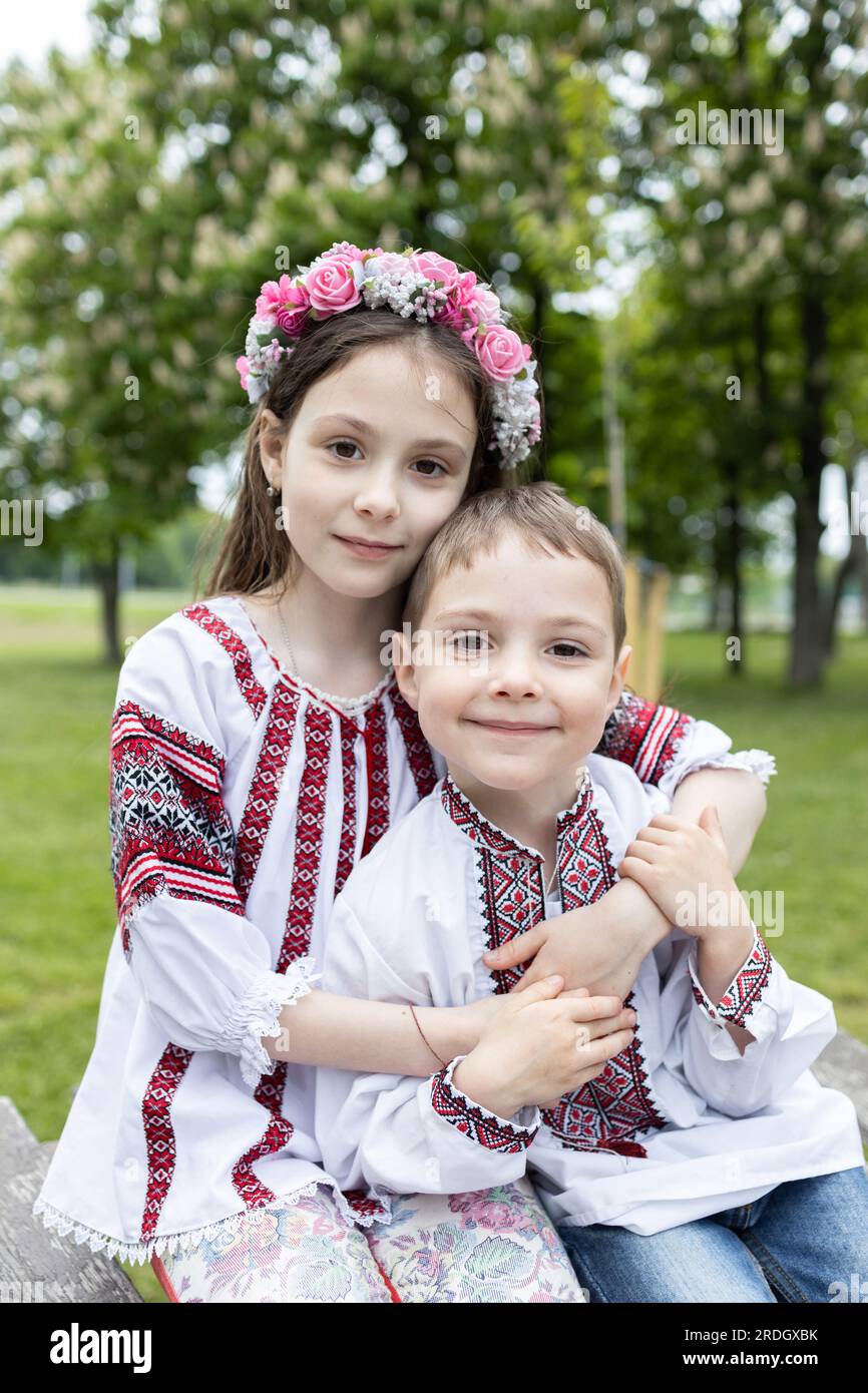 Carini ragazza e ragazzo, fratello e sorella, in abiti ucraini ricamati nazionali sono seduti uno accanto all'altro Foto Stock
