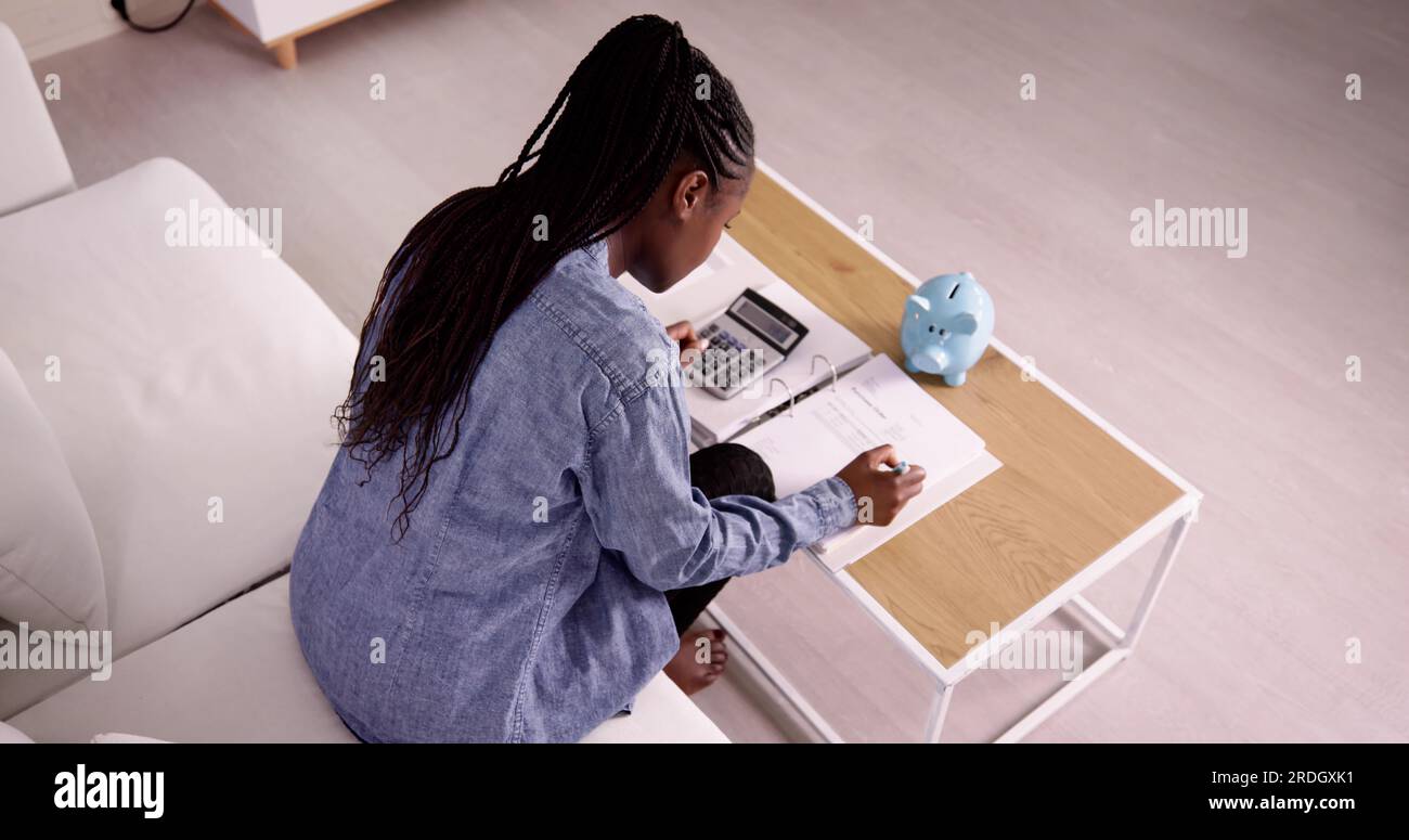 Giovane donna africana calcolo fattura con la calcolatrice Foto Stock