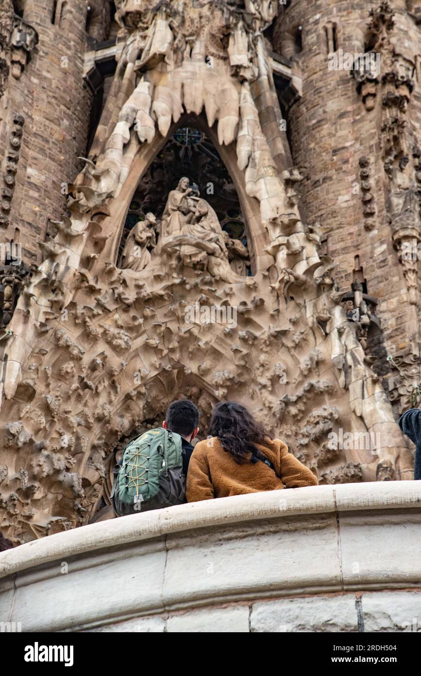 Barcellona, Spagna - 2 febbraio 2022: Una giovane coppia guarda la facciata della Sagrada Familia, la principale attrazione turistica Foto Stock