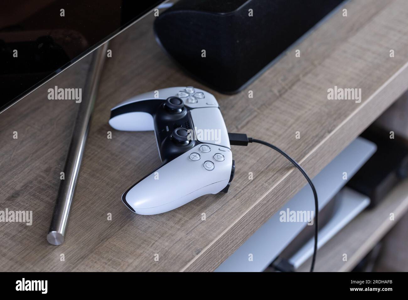 Brecht, Belgio - 14 luglio 2023: Un ritratto di un controller playstation 5 originale bianco e nero che si ricarica con un cavo usb c collegato al po Foto Stock