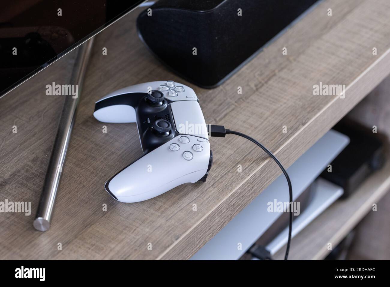Brecht, Belgio - 14 luglio 2023: Un ritratto di un controller playstation 5 originale in bianco e nero che si ricarica con un cavo usb c collegato al po Foto Stock