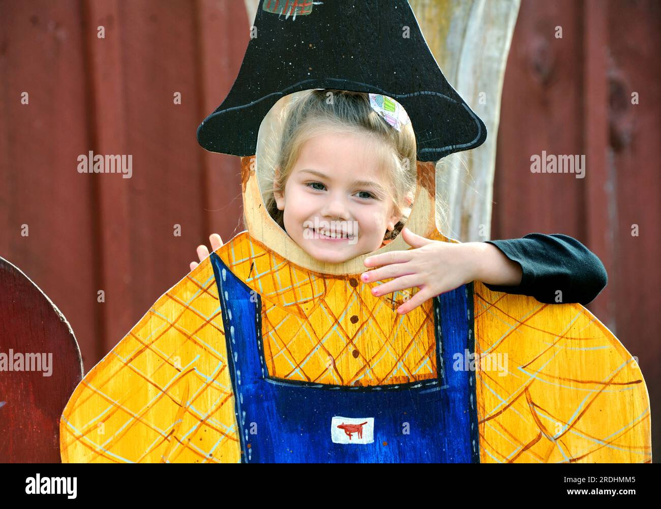 La bambina punta la testa attraverso una replica in legno di uno scarabeo 'contadino' ad un festival del raccolto in Tennessee. Sorride. Foto Stock