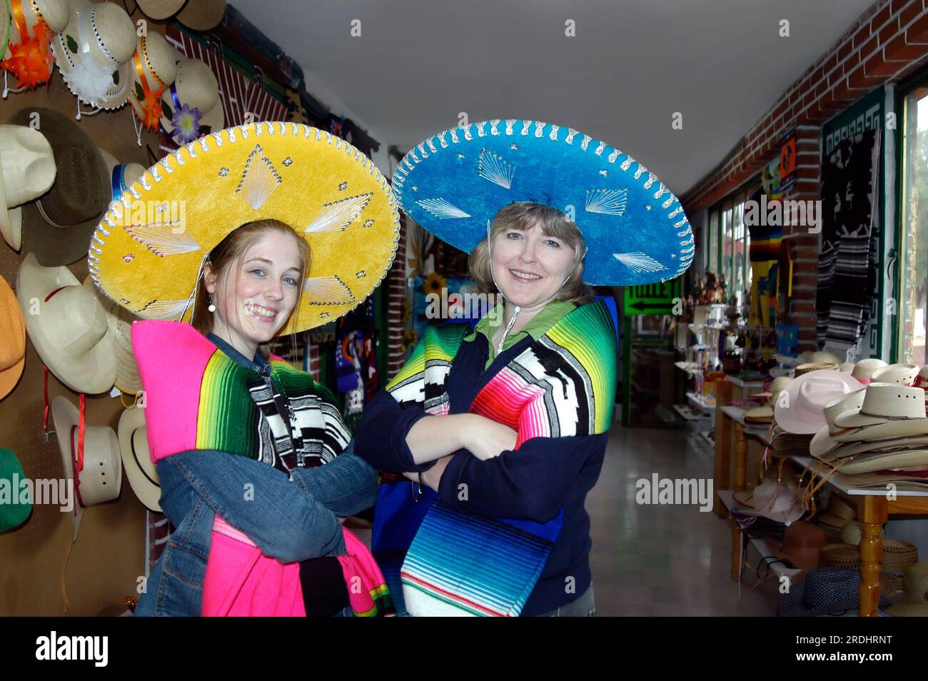 Sombreros messicani modello madre e figlia e coperte colorate. La madre indossa un cappello blu brillante e la figlia indossa un giallo. Entrambi touris Foto Stock