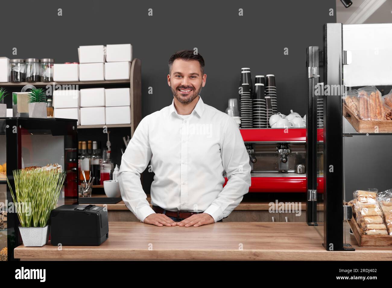 Ritratto di un felice imprenditore alla scrivania nel suo caffè Foto Stock