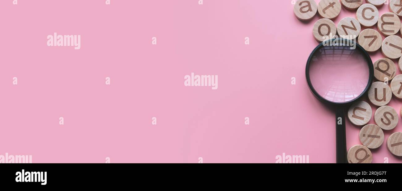 Concetto di apprendimento dell'inglese, ricerca di parole e informazioni. Lettera alfabetica inglese e lente di ingrandimento. Sfondo rosa con spazio di copia. Foto Stock
