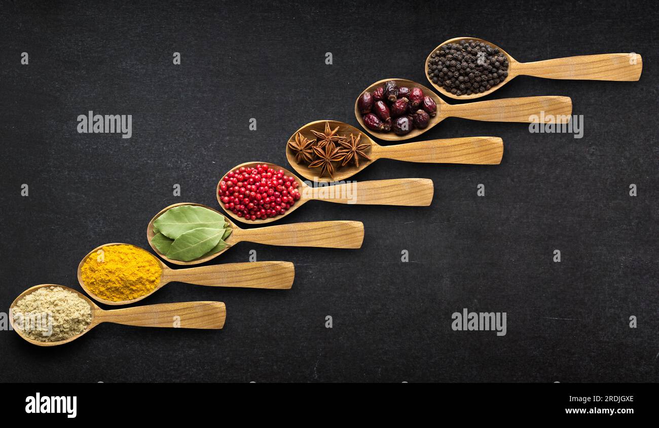 Spezie indiane in cucchiaio sullo sfondo del tavolo, vista dall'alto Foto Stock