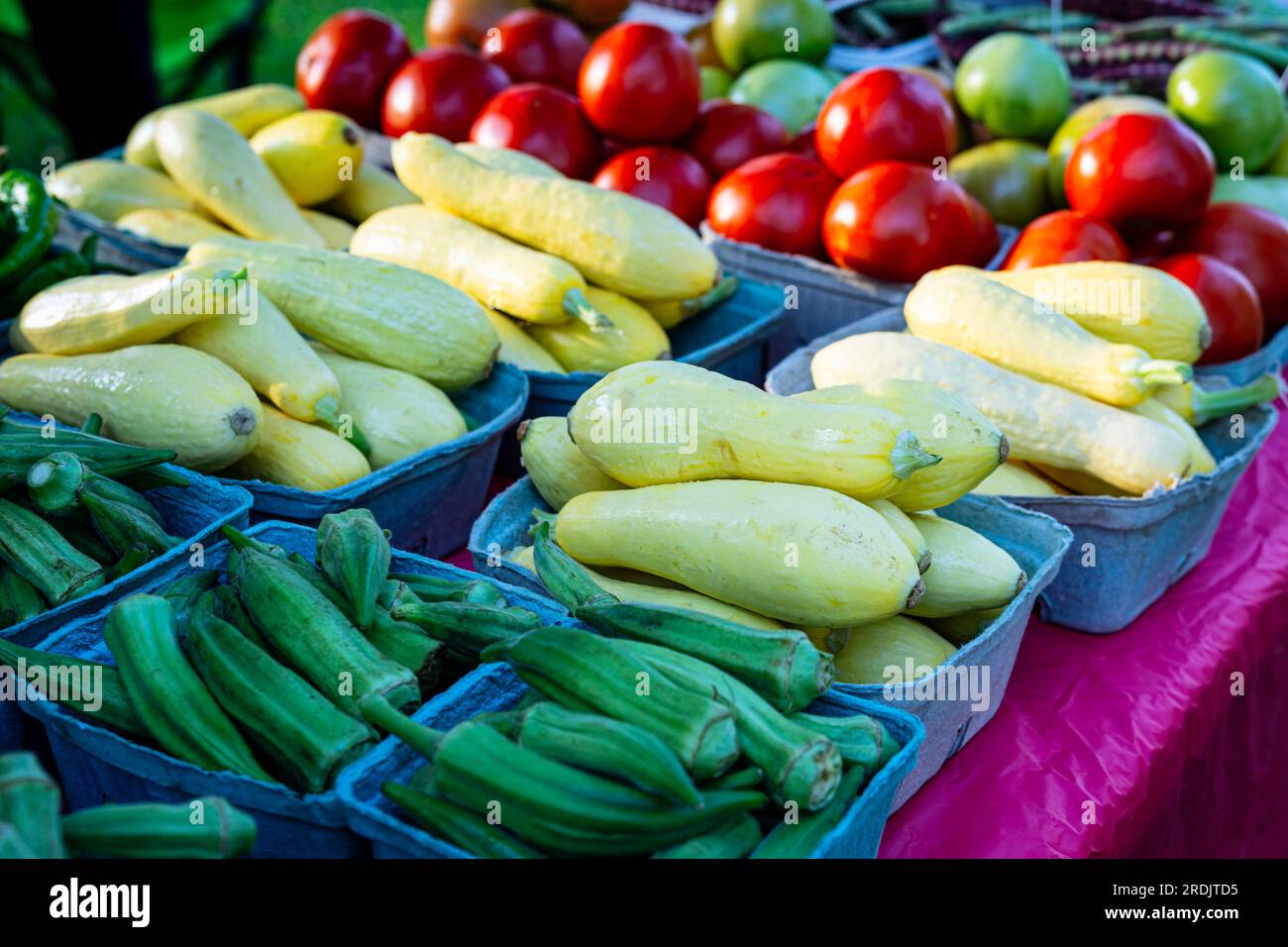 Verdure fresche assortite esposte in cartoni su un tavolo in un mercato agricolo a luglio. Foto Stock