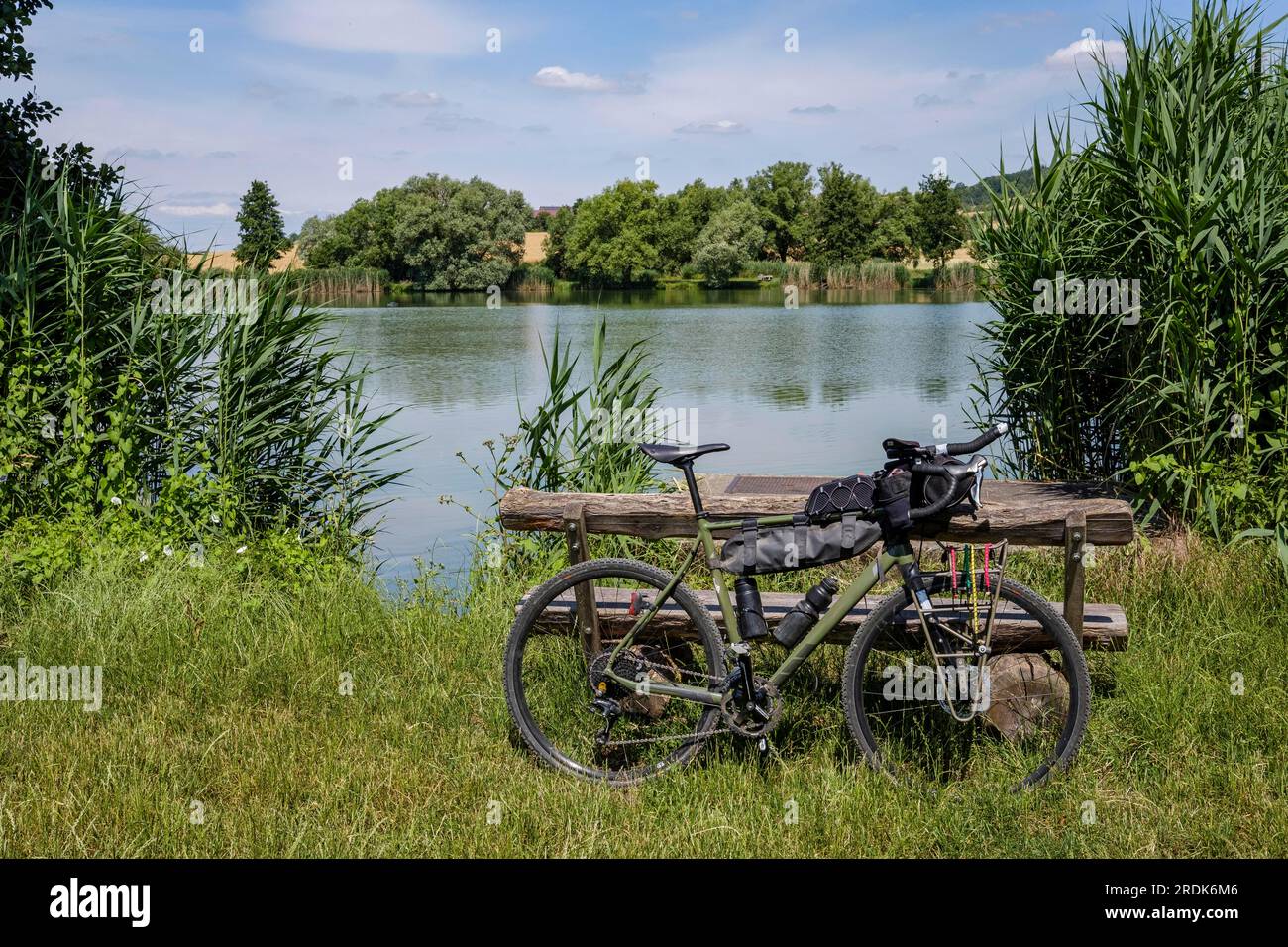 Con la bici in ghiaia nella natura, bassa Franconia, lago, specchio d'acqua, cielo blu, trekking, equipaggiamento, posto a sedere Foto Stock