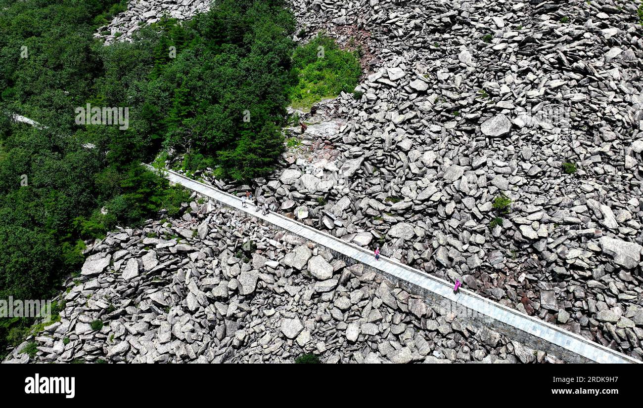 XI'an. 21 luglio 2023. Questa foto aerea scattata il 21 luglio 2023 mostra i visitatori che passano il mare di roccia presso il Parco forestale nazionale di Zhuque a Xi'an, nella provincia dello Shaanxi della Cina nord-occidentale. Il parco, situato nel corso superiore del fiume Laohe orientale e nel nord dei monti Qinling, copre un'area di 2.621 ettari, e il suo punto più alto il picco Bingjing ha un'altitudine di 3.015 metri. Lungo la strada che conduce alla vetta si possono ammirare paesaggi incredibili come la foresta vergine, i resti di ghiacciai e il mare nuvoloso. Crediti: Liu Xiao/Xinhua/Alamy Live News Foto Stock