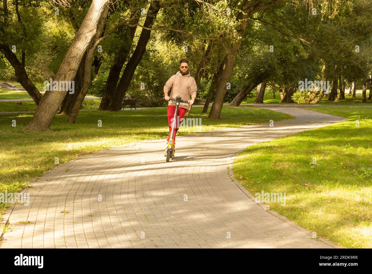 Il concetto di svago giovanile. Il ragazzo guida uno scooter elettrico lungo il percorso del parco Foto Stock