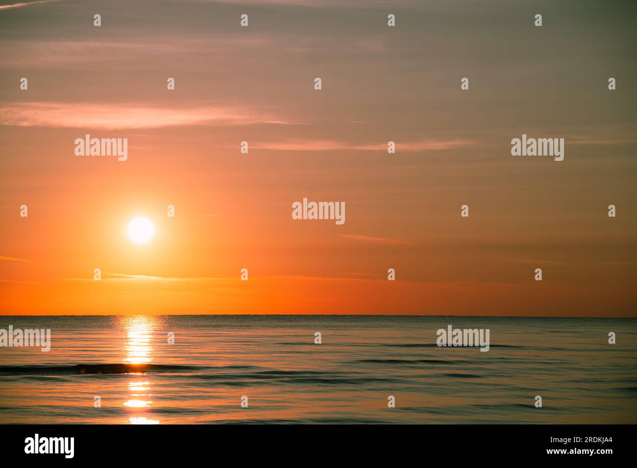 I raggi del sole si riflettono nelle onde luminose, creando riflessi danzanti sull'acqua. La bellezza dell'alba sulla spiaggia può ispirare nuove idee e rinnovare il tuo Foto Stock