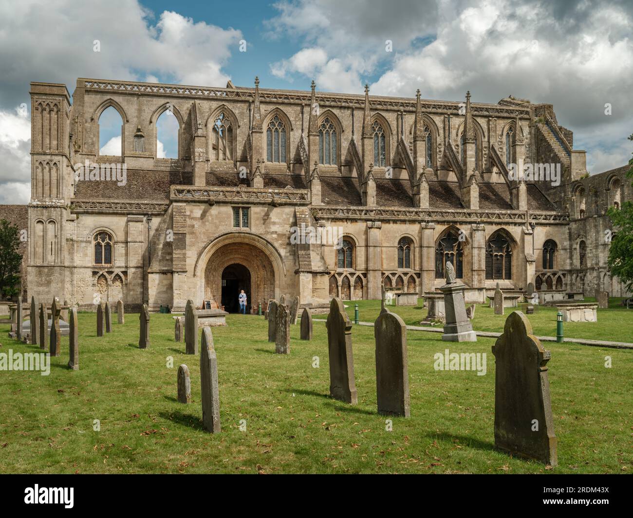 Il sole d'estate illumina la facciata della storica abbazia nella città di mercato di Cotswold a Malmesbury. La storica abbazia fu fondata come benedettina Foto Stock