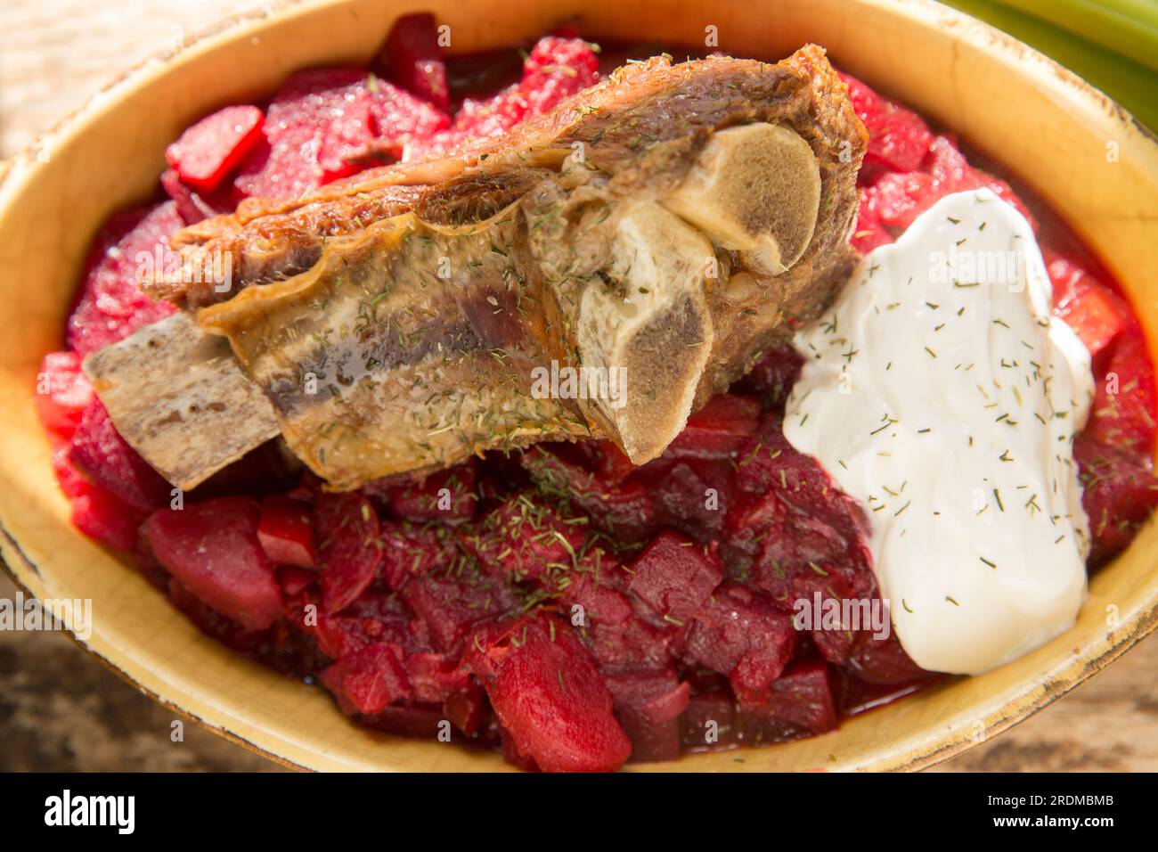 Zuppa di Borscht fatta in casa servita con costolette di manzo cotte lentamente e un pizzico di creme fraiche. Esposto su un tagliere di legno. Inghilterra Regno Unito GB Foto Stock