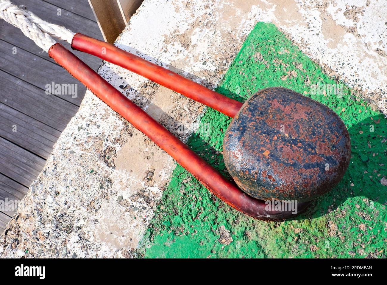 Una linea di attracco (una corda per ormeggio) su un grande dissuasore, protetta da una manica in pelle. Foto Stock