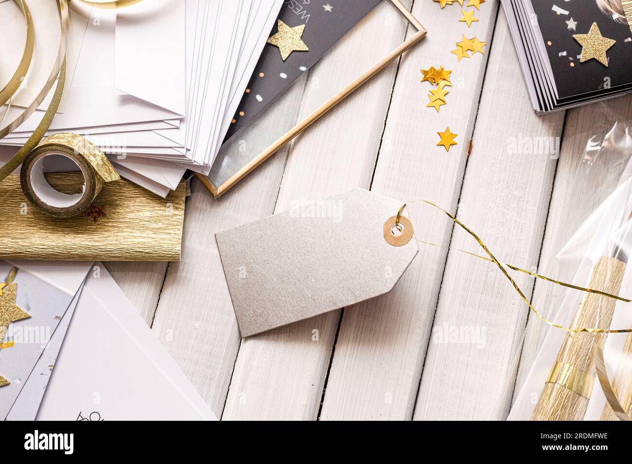 Elegante confezione regalo e cartellini con dettagli dorati e forme a stella. Elegante confezione regalo con stelle dorate, carta a righe e cartellino regalo vuoto Foto Stock