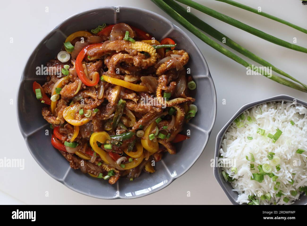 Pannocchie di mais servite insieme al riso al burro con cipolle primaverili. Un piatto indo cinese con croccante mais fritto in una salsa piccante con cipolla saltata Foto Stock