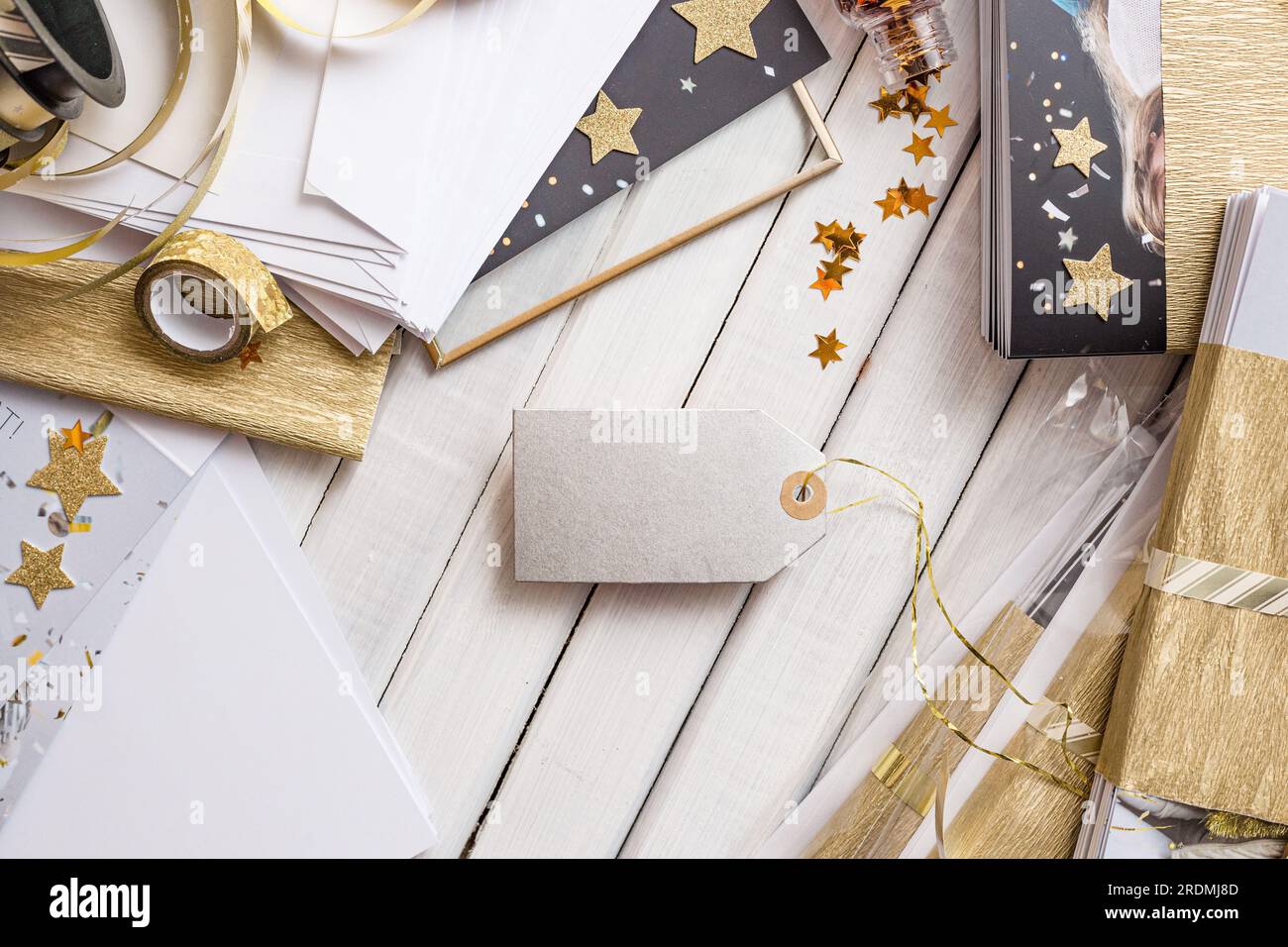 Elegante confezione regalo e cartellini con dettagli dorati e forme a stella. Elegante confezione regalo con stelle dorate, carta a righe e cartellino regalo vuoto Foto Stock